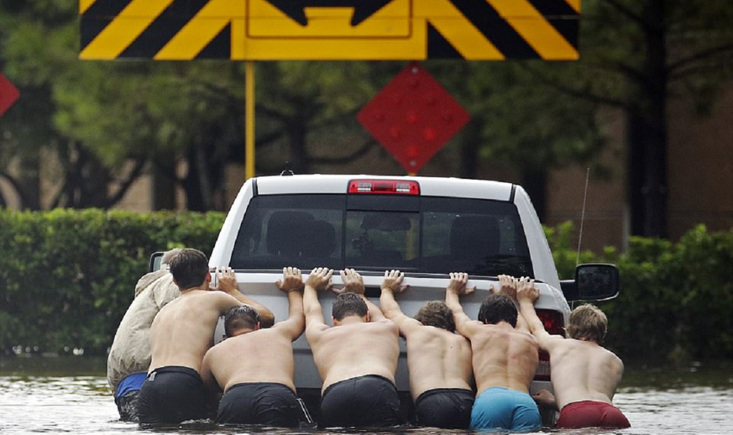  Χιούστον: Νεαροί έβγαλαν τα πουκάμισα τους για να σπρώξουν ένα φορτηγό που κόλλησε μέσα στο νερό - Φωτογραφία: AP