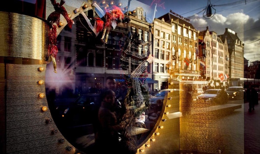 Χριστουγεννιάτικοι στολισμοί αντικατοπτρίζονται στη βιτρίνα εμπορικού καταστήματος στο κέντρο του Άμστερνταμ - Picture: EPA / KOEN VAN WEEL